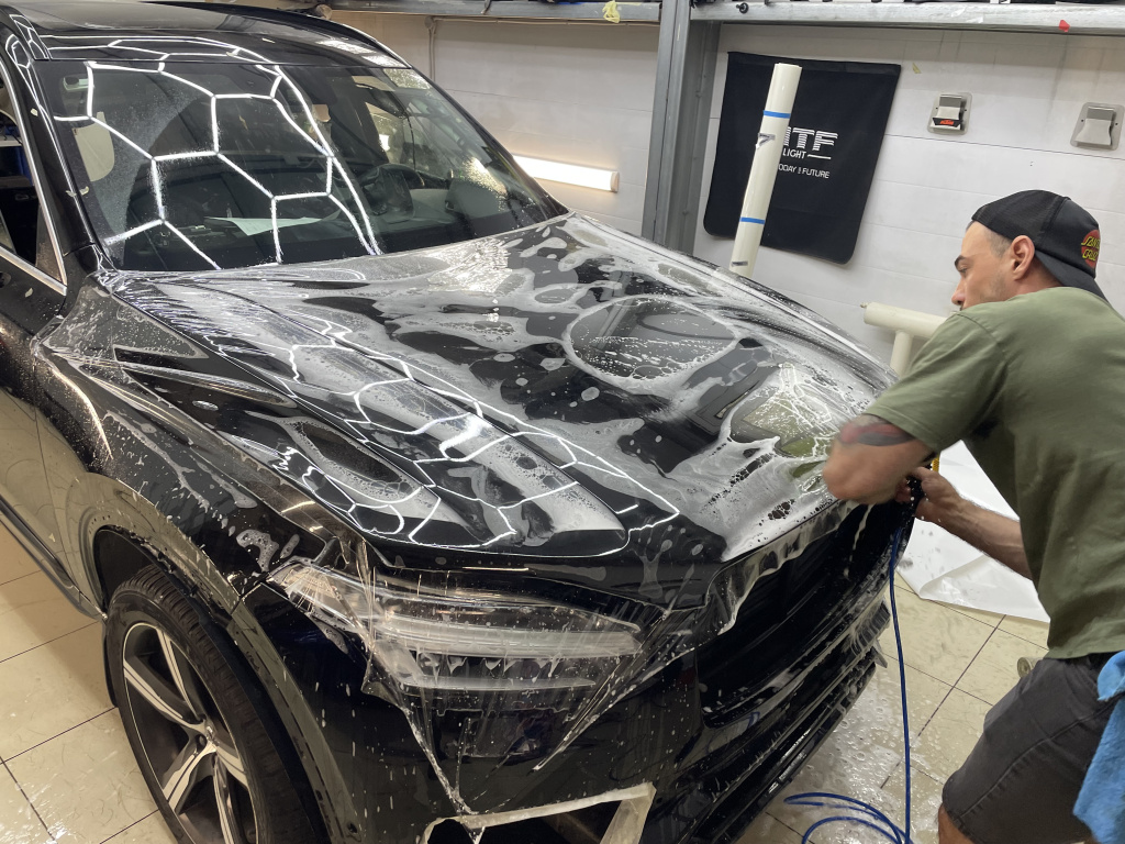Процесс разглаживания полиуретановой бронепленки на капоте автомобиля